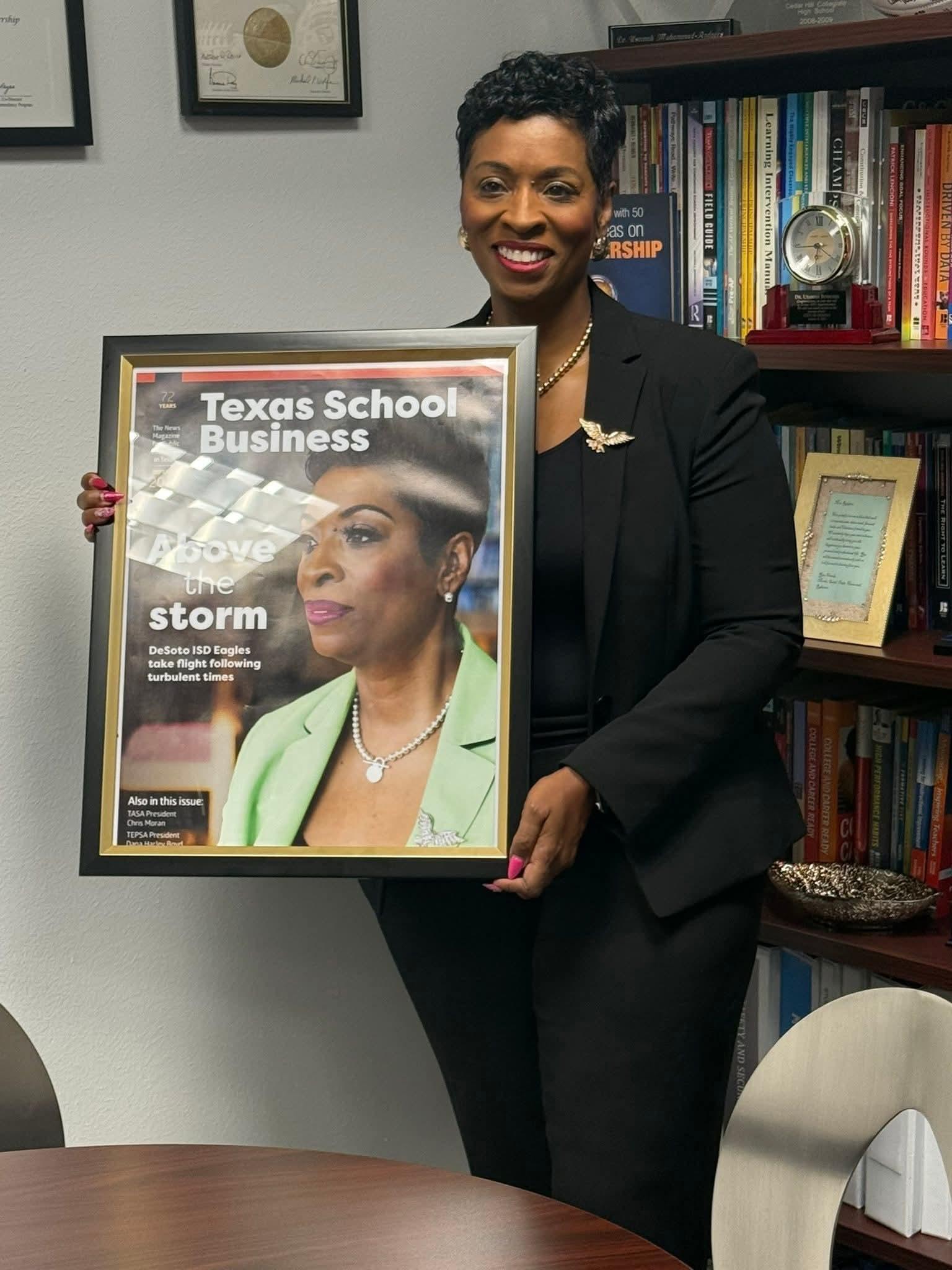 Woman holding framed Texas School Business cover.