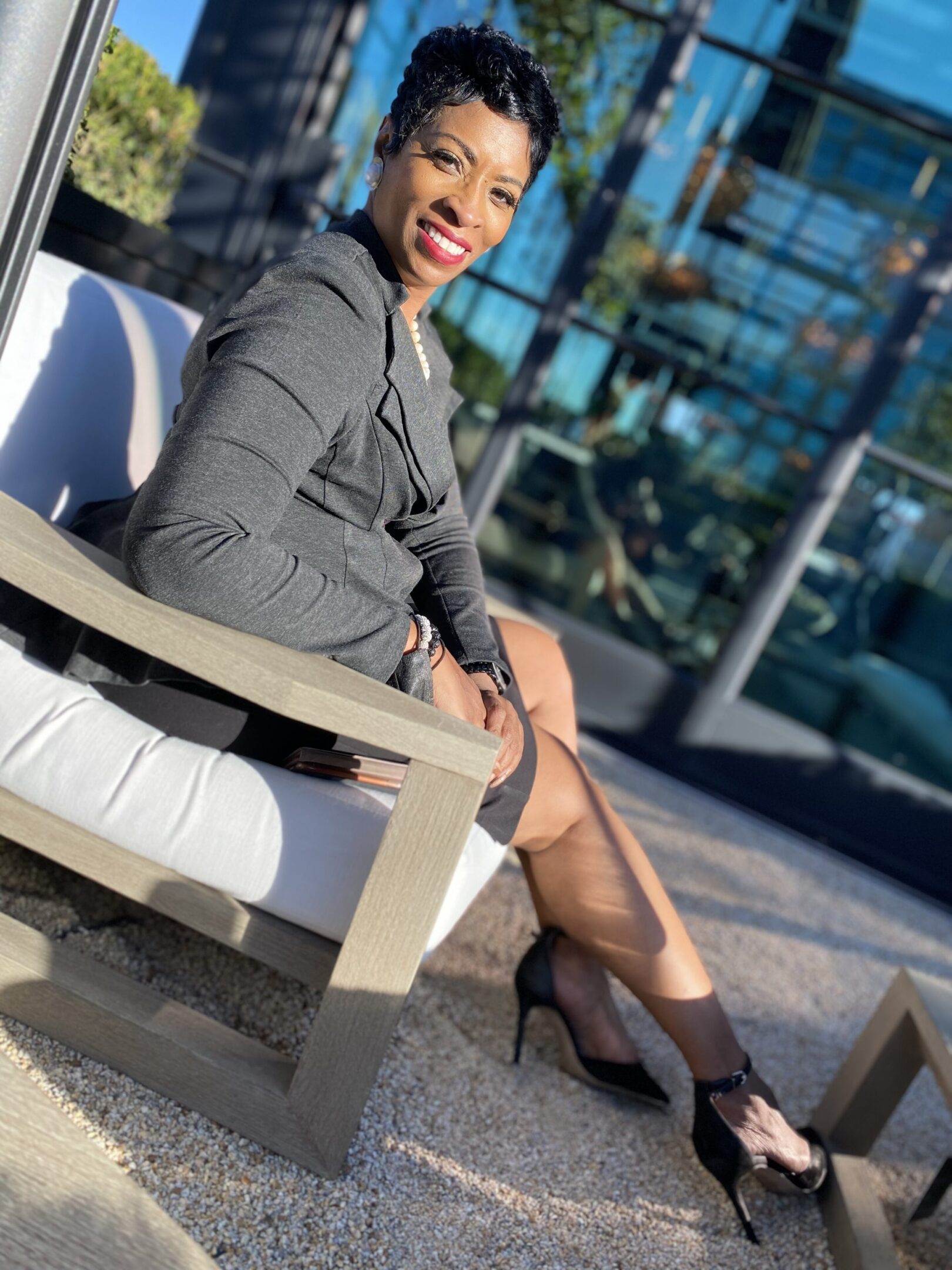 Smiling woman sitting outdoors in sunlight.