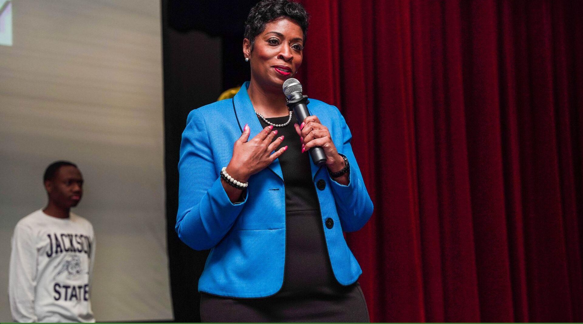 Person speaking on stage with microphone.